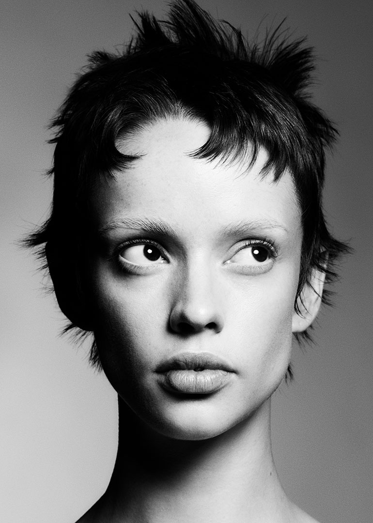 Close-up portrait of model with short choppy dark pixie cut and textured fringe, black and white